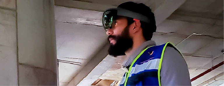 Un hombre con barba, vestido con un chaleco de alta visibilidad y gafas inteligentes, se encuentra en un lugar cerrado del Centro Comercial Sentura