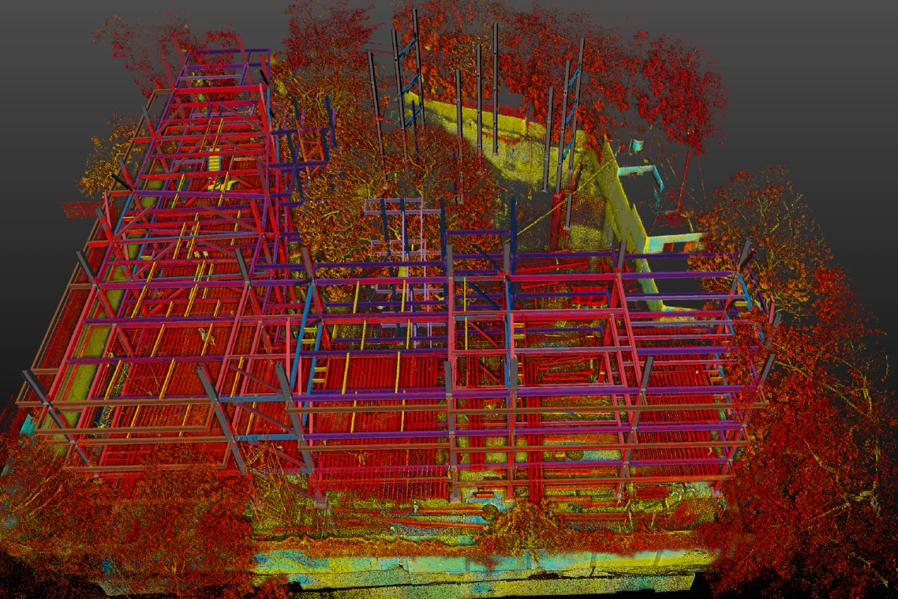 A building with red and blue scaffolding rises as part of the Corteza residential housing development.