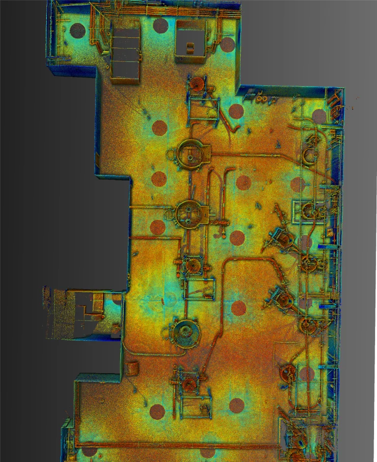 Un escaneo LiDAR en Monterrey de arriba abajo, codificado por colores, de una sala industrial con maquinaria, tuberías y plataformas circulares; los colores indican distintos niveles de elevación o intensidad, que van del azul (bajo) al rojo (alto).