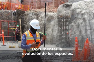 Un trabajador de la construcción con casco blanco y chaleco de seguridad utiliza un teléfono y una herramienta topográfica en una obra en construcción. Se ven barras de refuerzo y una red naranja. El texto dice: Fotografía Digital Técnica para documentar la evolución de los espacios.