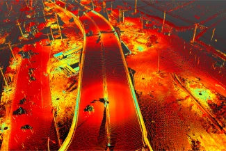 Escaneado LiDAR de una autopista y sus alrededores que muestra carreteras, barreras y estructuras en tonos rojos, naranjas y amarillos para ilustrar la elevación y los detalles de la superficie.