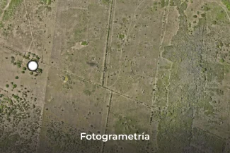 Vista aérea de un paisaje seco y herboso con vegetación verde dispersa y caminos de tierra que se cruzan. Un círculo blanco señala un punto. En la parte inferior aparecen las palabras Fotogrametría