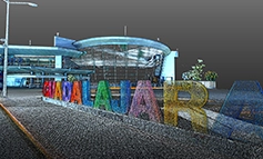A modern building with large, colorful letters spelling GUADALAJARA stands on a paved area, showcasing Reality Capture techniques amid greenery and a cloudy sky in the background.