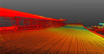 Una imagen coloreada digitalmente, que recuerda a los escaneados LiDAR, muestra una larga pasarela o puente industrial desde un ángulo bajo. Las superficies y las barandillas se tiñen de rojos, amarillos y azules brillantes sobre un cielo gris, creando un efecto similar al de un mapa de calor.
