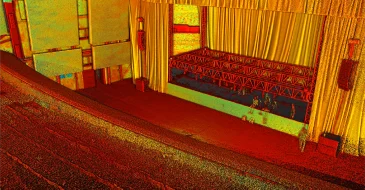 Colorida imagen de estilo puntillista de un teatro vacío con asientos rojos, un escenario en construcción, cortinas amarillas y andamios, capturada desde un ángulo elevado como si se viera a través de una perspectiva Escaneo LiDAR CDMX.