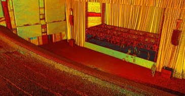 Nube de puntos de un teatro vacío con filas de asientos, un escenario con andamios y grandes telones: sus tonos surrealistas evocan los vibrantes resultados de un Escaneo LiDAR CDMX.