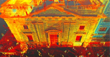 Una colorida nube de puntos LiDAR 3D escaneada de un edificio clásico con columnas, fachada detallada y personas como pequeños puntos a ras de suelo. La imagen utiliza amarillo, naranja, rojo, azul y verde para mapear los datos del escaneado.